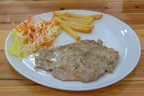 Pork steak with French fries and salad.