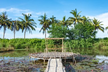 Bambu geçit ve bambu kulübe gölet üzerinde.