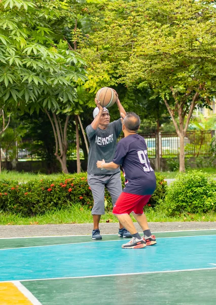 Stary człowiek zadowolony z ćwiczeń aby grać w koszykówkę w Nonthaburi Park Bangyai w Tajlandii. 22 Sierpień 2018 r. — Zdjęcie stockowe
