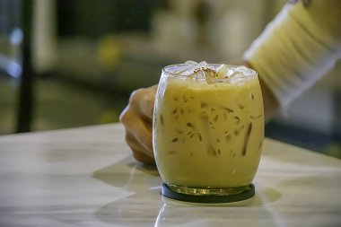 Masada bir bardak buzlu kahve tutan el.