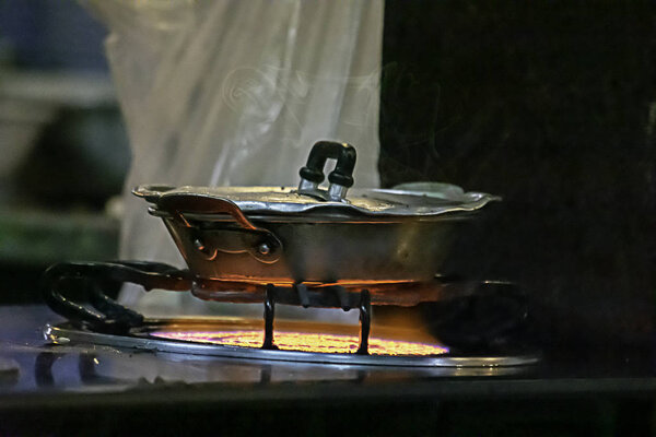 Stainless steel pan on the stove with a yellow flame.