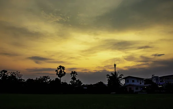 Beautiful light of Sunset with clouds in the sky reflection behind the building and paddy fields.