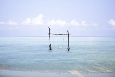 Denizde ahşaptan yapılmış salıncak sandalyeler Arka plan gökyüzü ve bulut.