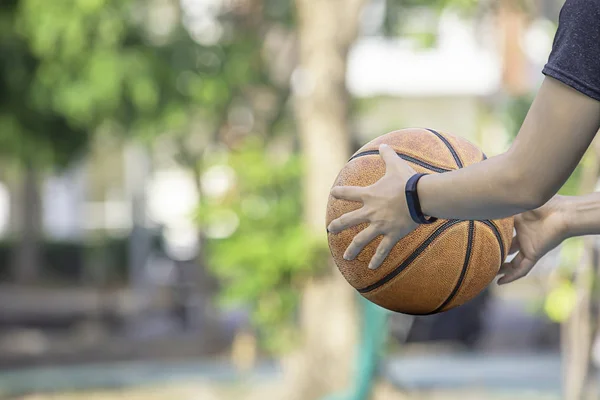 Leder-Basketball in der Hand einer Frau mit einer Uhr Hintergrund verschwimmen Baum in Park. — Stockfoto