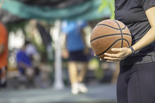 Leder-Basketball in der Hand einer Frau mit einer Uhr Hintergrund verschwimmen Baum in Park. — Stockfoto