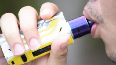 Ağızdan duman adam ve elinde elektronik sigara.