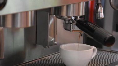 Kahve makinesinden gelen su beyaz bardaktan aşağı akıyor..