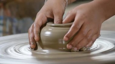 Parmaklar dönen bir tepsi üzerinde şekillenmiş kil pot.
