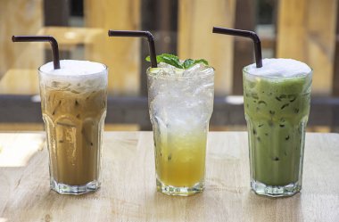 Buzlu kahve, ballı limonlu gazoz ve ahşap masada camda çilekli smoothie..