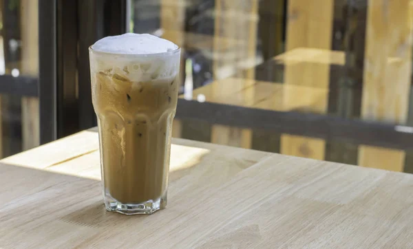 Iced Coffee in glass on the wooden table Background glass windows.