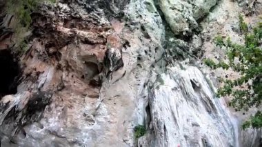 Video kask takan turistler, Tayland 'daki Krabi' de Phra Nang Mağara Sahili 'nde halat koruması ile tırmanıyorlar. 28 Ekim 2019