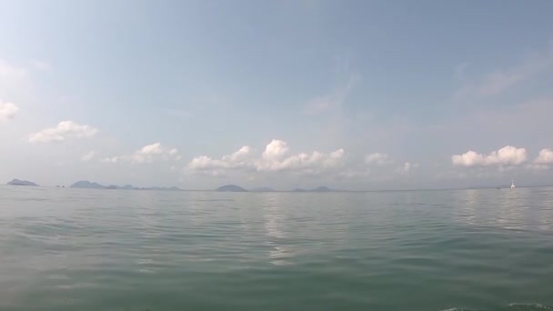Voir la vidéo sur un bateau conduisant dans la mer et éclaboussant l'eau Arrière-plan île et nuages dans le ciel lumineux . — Video