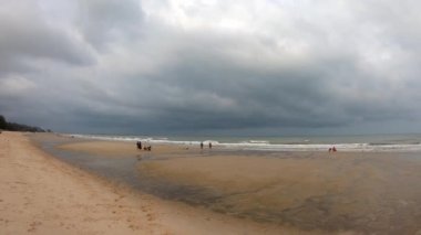 Video, kumsaldaki turistlerin solundan sağa, arka plandaki deniz dalgaları ve Cha am plajındaki Karadeniz yağmur bulutları şeklinde hareket ediyor. Tayland 'da Phetchaburi. 15 Mart 2020