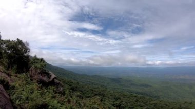 Video, bulutların solundan sağa doğru hareket ediyor. Gün ışığında gökyüzünde hareket ediyor ve ağaçlar rüzgarda sallanıyor. Phu Hin Rong Kla, Phetchabun, Tayland 'da..