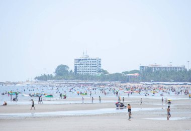 Birçok turist, Tayland 'da Chonburi, Bangsaen Sahili' ndeki sahillerde, arka planda ve büyük binalarda yürürler. 21 Haziran 2020