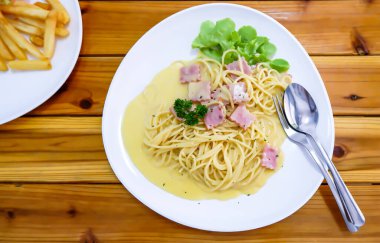 Spagetti, ahşap bir masada beyaz tabakta kızarmış peynir..