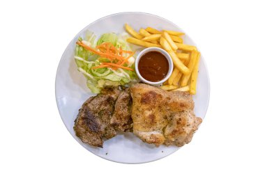 Karabiberli domuz bifteği, patates kızartması ve salatayla kaplı tavuk, kesme yolu olan beyaz bir arka planda..