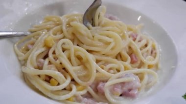 Beyaz tabakta çatallı kızarmış peynirli spagetti..