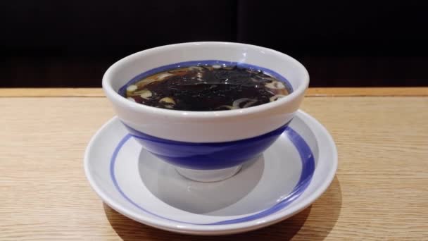 Fumée blanche flottant du bouillon avec algues et oignons de printemps dans une tasse blanche sur la table. — Video