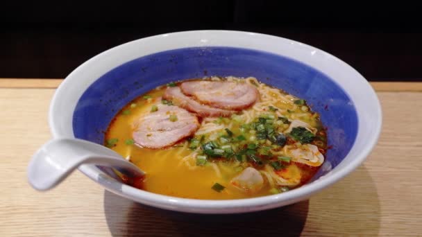 Fumée blanche flottant de la nouille Ramen au porc avec algues et oignons de printemps dans une tasse blanche sur la table. — Video