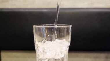 Yavaş şarjör. Su, ahşap masadaki buzlu bardağa döküldü..