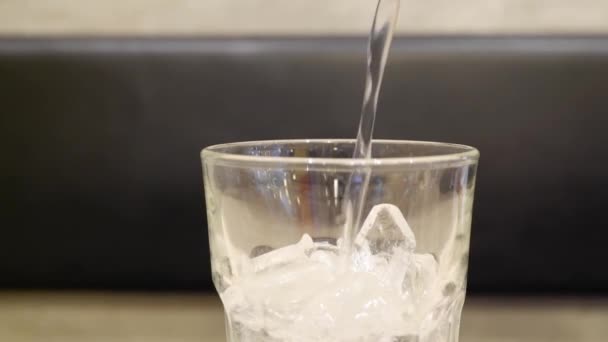 L'eau a été versée dans un verre avec de la glace sur une table en bois.