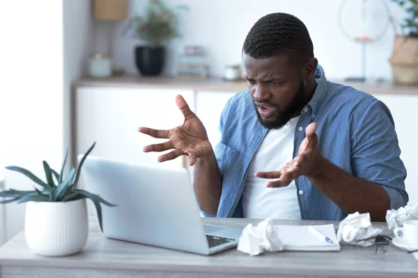 Furious man mad at slow working computer sitting at his desk