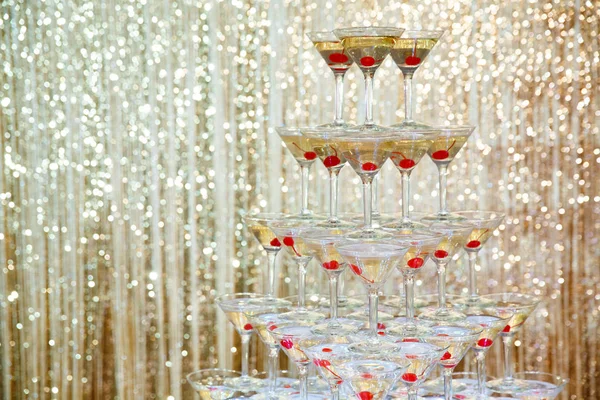 Sparkling champagne pyramid, tower of glasses at the party in front of golden wall