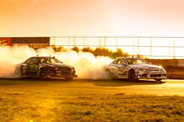 MOSCOW, RUSSIA - MAY 05, 2018: cars are drifting at motordrome in the light of sunset, first stage of Russian Drift Series 2018, Moscow Raceway motordrome clipart