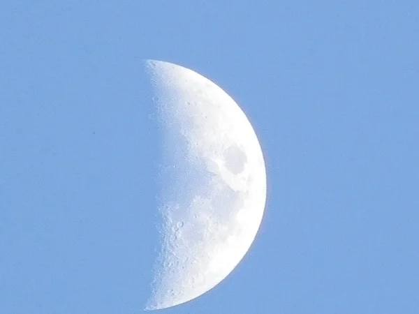 The moon in the blue sky.