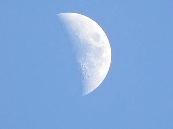The moon in the blue sky.