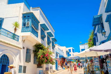 SIDI BOU SAID, TUNISIA - JULY 05, 2017: Main shopping street with walking tourists in white blue town. clipart