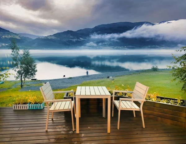 Wooden terrace with view of lake shore at foggy cloudy evening.