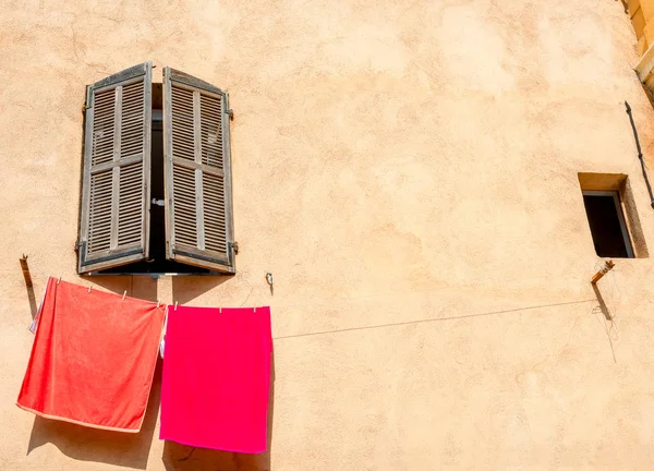 Κόκκινες πετσέτες στη γραμμή των ρούχων ενάντια στον κίτρινο τοίχο του σπιτιού με νίκη — Φωτογραφία Αρχείου