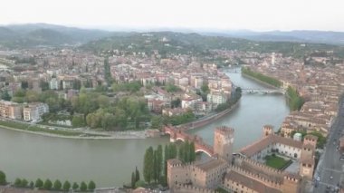 Verona, İtalya hava atış ile tipik İtalyan dairesi çatıları, gün batımında sokak kalabalıklar, Roma Colosseum Arena, Adige Nehri, Santuario Madonna di Lourdes, dağlar Lessinia Tabiat Parkı. 
