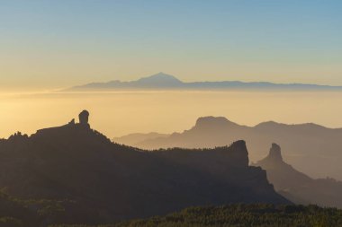 Gün batımı ışık karşı siluetleri Roque Nublo ve Bentayga. Pico de Teide arka plan üzerinde. Gran Canaria, Kanarya Adaları, İspanya