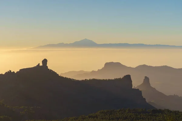 Gün batımı ışık karşı siluetleri Roque Nublo ve Bentayga. Pico de Teide arka plan üzerinde. Gran Canaria, Kanarya Adaları, İspanya