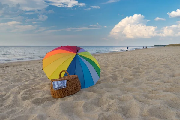 Deniz kıyısına karşı şemsiye ve piknik sepeti