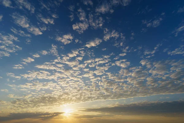 Cirrocumulus bulutları ile mavi gökyüzü üzerinde yükselen güneş