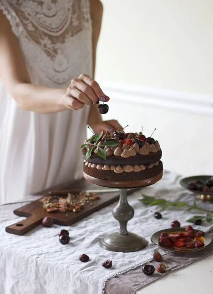 Kiraz ile çikolatalı kek yapma hazırlama, çilek yaz arka planda, kadın eli süsleyin pasta