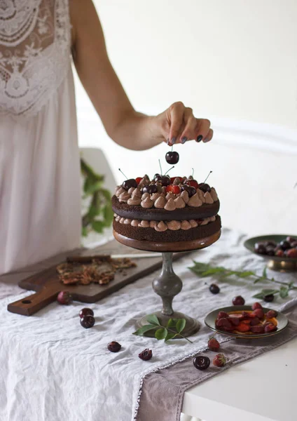 Kiraz ile çikolatalı kek yapma hazırlama, çilek yaz arka planda, kadın eli süsleyin pasta