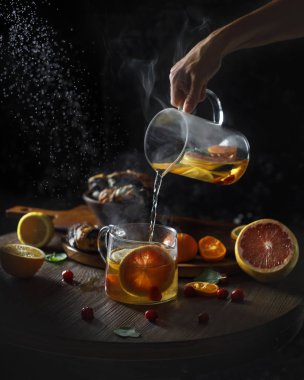 Rustik kış narenciye sıcak çay. Cam çaydanlık üzerinden Çin yeşil çay buharla küçük su ısıtıcısı dökülen el