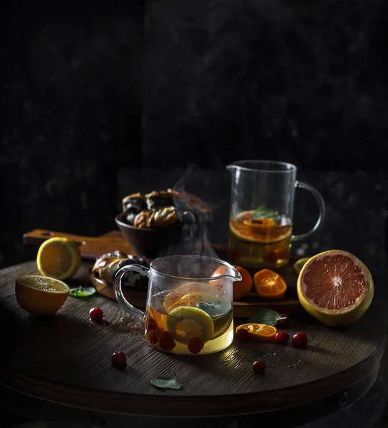 Rustik kış narenciye mulled şarap çay. Rustik koyu arka plan üzerinde buhar ile küçük su ısıtıcısı