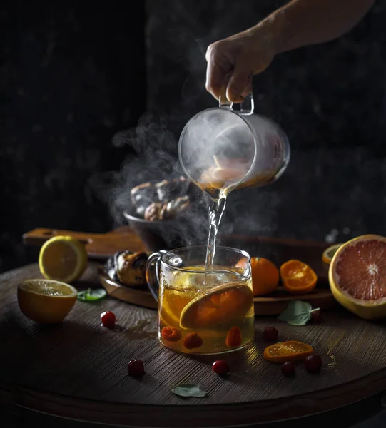 Rustik kış narenciye sıcak çay. Cam çaydanlık üzerinden Çin yeşil çay buharla küçük su ısıtıcısı dökülen el