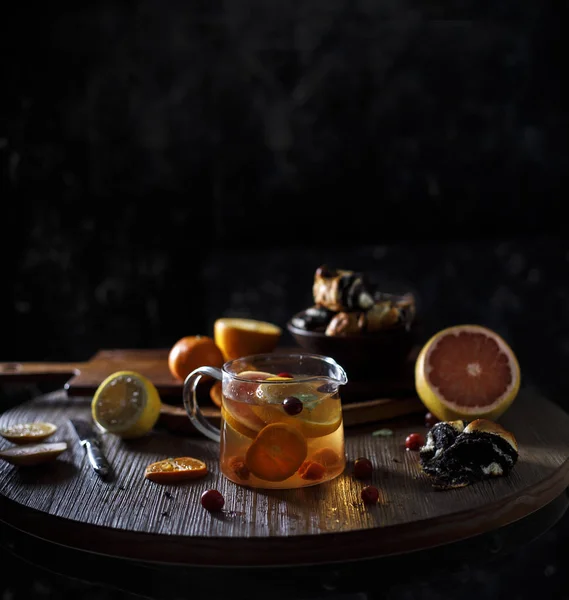 Rustik kış narenciye mulled şarap çay. Rustik koyu arka plan üzerinde buhar ile küçük su ısıtıcısı