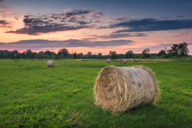 Günbatımı üzerinde çayır ve saman balya