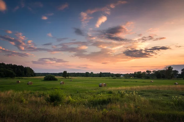 Günbatımı üzerinde çayır ve saman balya