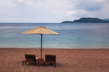 Şezlong ve şemsiye Adriyatik Denizi üzerinde sahilde Budva, Karadağ yakın: