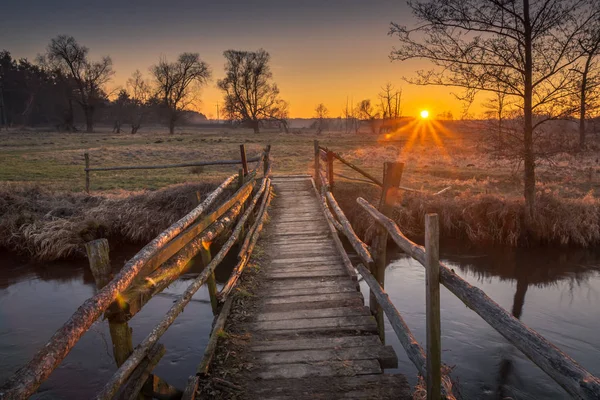 Sonnenuntergang über der Holzbrücke im Tal des Flusses Jeziorka ne — Stockfoto