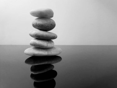 Balanced zen stones on a black table against grey background. Concept of harmony, balance and meditation, spa, relax. Copy space in black and white clipart